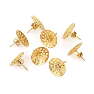 May include: Gold-colored stud earrings with a perforated, oval design. The earrings have a post and butterfly backing. The earrings are displayed on a white background. The earrings are a jewelry accessory.
