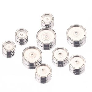 May include: A collection of silver-colored, round metal bezel settings. Each setting has a flat, recessed area for inserting a design or stone. The settings vary in size and have small holes on the sides.