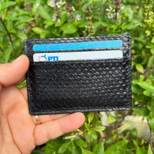 Puede incluir: Una taza de cer&aacute;mica blanca con un asa negra y el texto "But First, Coffee" en negro, en negrita. La taza est&aacute; sobre una superficie blanca.