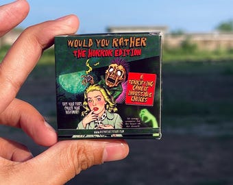 May include: A small, square box for "Would You Rather: The Horror Edition" game. The box features a green background with a zombie and a woman in distress. Text includes "Face Your Fears, Choose Your Nightmare!" and "A Terrifying Game of Impossible Choices."