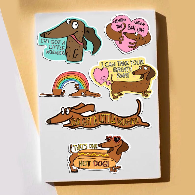 May include: A collection of colorful dachshund stickers on a white background. The stickers feature cartoon dachshunds with various phrases, including "I've got a little wiener" and "That's one hot dog!" Other stickers include a rainbow and heart-shaped designs.