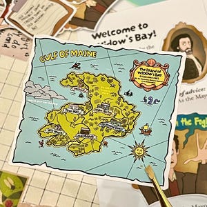 Könnte beinhalten: Ein quadratischer Aufkleber mit einer Karte des Golfs von Maine und der Insel Widow's Bay. Die Karte enthält Beschriftungen für Town Hall, Widow's Bay Inn, Driftwood Diner, Salty Whale und Local Museum sowie einen Sonnenkompass und nautische Motive.