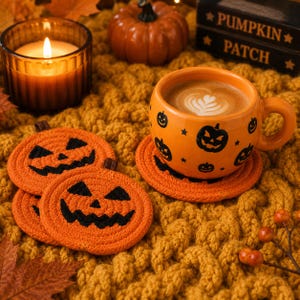 Puede incluir: Una taza de cerámica naranja con caras de calabaza negras y estrellas, llena de café, sobre un posavasos de cuerda naranja a juego. Dos posavasos de cuerda naranja adicionales con caras de calabaza negras están apilados cerca.