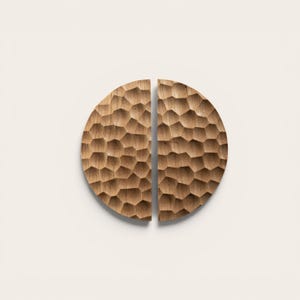 Könnte beinhalten: Zwei halbkreisförmige Holzschrankgriffe mit einem strukturierten, wabenartigen Muster. Die Griffe haben eine warme braune Farbe und scheinen aus Naturholz zu bestehen. Sie sind für die Montage an einem Schrank oder einer Schublade konzipiert.