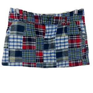 以下が含まれることがあります： 青、赤、緑、白の色合いのチェック柄を組み合わせたパッチワークスカート。 スカートにはベルトループ付きのウエストバンドとジッパー開閉部があります。 軽量生地で作られています。