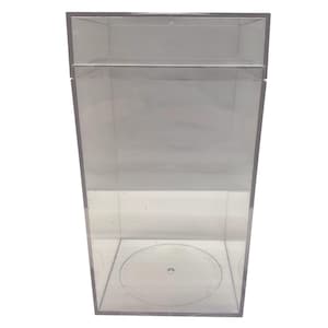 Puede incluir: Una vitrina rectangular transparente con tapa abatible. La vitrina está hecha de acrílico transparente y presenta un diseño circular en la base. Adecuada para exhibir objetos de colección u otros artículos.