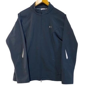 May include: A black zip-up jacket with a stand-up collar. The jacket features a small silver logo on the chest and white accents on the sleeves. The jacket is hanging on a wooden hanger.