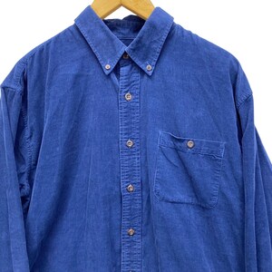 May include: A button-down, long-sleeve shirt in a solid blue color. The shirt has a button-down collar, a chest pocket, and buttons down the front and on the cuffs. The fabric appears to be corduroy.