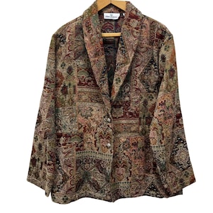 May include: A vintage blazer with a patchwork design. The jacket features a mix of floral and geometric patterns in shades of brown, red, green, and blue. It has a single-button closure and a classic lapel. The blazer is made of a textured fabric.