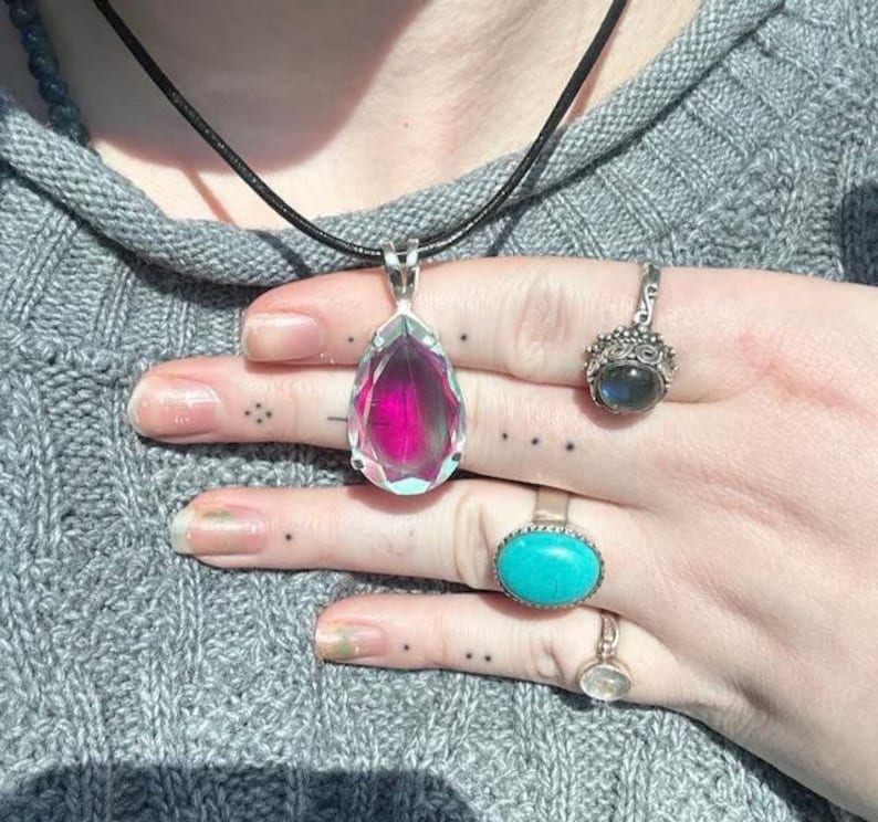 Close view of rainbow Angel Aura Quartz teardrop pendant set in solid 925 sterling silver. Dainty crystal necklace with mystical glow, perfect for everyday wear or meaningful gift giving.