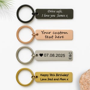 May include: Four keyrings with rectangular tags and various ring colours. The tags are engraved with text, including "Drive safe, I love you James x", "Your custom text here", a date, and a birthday message.