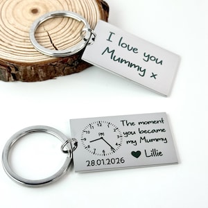 May include: Two silver rectangular keyrings. One reads "I love you Mummy x". The other has a clock design with the text "The moment you became my Mummy Lillie" and the date 28.01.2026.