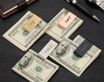 Puede incluir: Una colección de pinzas para billetes personalizadas en oro, oro rosa, plata y negro, cada una con una pila de billetes de 100 $. Las pinzas están grabadas con iniciales y nombres, incluyendo "OG", "A♥T", "Evelyn Joy" y "Luna Rae".