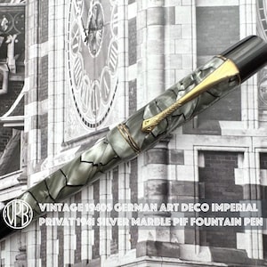 Può includere: Una penna stilografica con corpo marmorizzato argento e grigio, dotata di cappuccio e fondello neri. La penna presenta una clip e un anello di colore dorato. Il testo sull'immagine recita: VINTAGE 1940S GERMAN ART DECO IMPERIAL PRIVAT 1941 SILVER MARBLE PIF FOUNTAIN PEN.