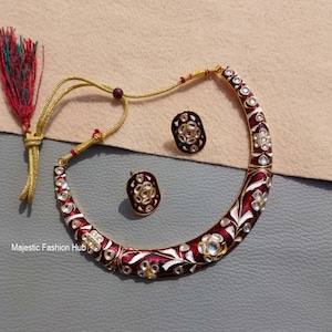 Peut inclure: Un collier en émail rouge et blanc et une paire de boucles d'oreilles assorties. Les bijoux présentent un motif floral avec des pierres précieuses transparentes. Le collier est de style ras du cou avec un cordon doré. Les boucles d'oreilles sont de forme ovale.