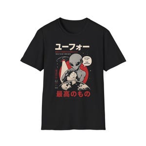 May include: A black short-sleeve t-shirt featuring a graphic of a grey alien petting a cat above Earth. The design includes a UFO, a red sun, and Japanese text with the English phrases "Taking the best from Earth" and "Petting a cat... Pure happiness."