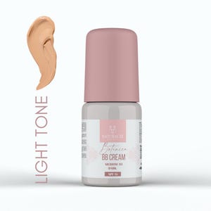 Peut inclure: Un flacon de crème BB Naturaliz Botanica dans une teinte claire. Le flacon est gris avec un bouchon rose et une étiquette indiquant "Medium to Dark" et "SPF 15". Une touche de crème est affichée à côté du flacon.