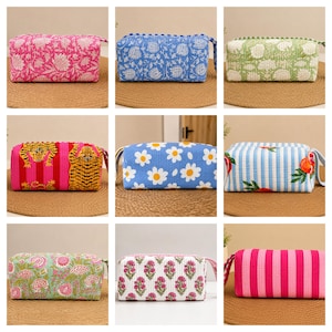 May include: A collection of nine rectangular quilted fabric pouches featuring various patterns including floral prints, tiger motifs, daisy designs, fruit illustrations, and vertical stripes in vibrant colors like pink, blue, green, and white.