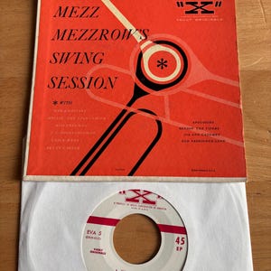 Peut inclure: Une pochette d'album vinyle vintage et un disque. La pochette est orange avec des graphiques noirs et blancs et le texte "MEZZ MEZZROW'S SWING SESSION". Le disque est blanc avec du texte rouge et un centre noir.