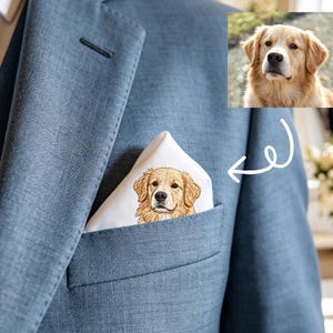 May include: A pale blue suit with a white pocket square embroidered with a golden retriever dog. The pocket square is folded in the breast pocket. A close-up of the dog's face is also shown. The suit is worn with a white shirt and tie.