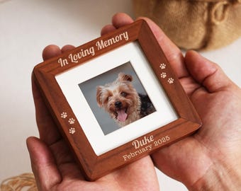 Pode incluir: Uma moldura quadrada de madeira com uma foto de um cão. A moldura é gravada com as palavras "In Loving Memory", pegadas, o nome "Duke" e a data "Fevereiro 2025".