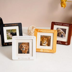 May include: A collection of square picture frames in black, white, and wood tones, each holding a photo of a dog. The frames are inscribed with phrases like "Best Friends" and "Forever Loved," along with the dog's name and paw prints.