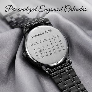 K&ouml;nnte beinhalten: Eine schwarze Armbanduhr mit einem Edelstahl-Kalenderzifferblatt. Das Zifferblatt ist mit dem Monat Dezember 2026 graviert und das Datum des 12. ist mit einem Herzsymbol hervorgehoben. Die Uhr hat ein schwarzes Metallarmband und der Text "Personalized Engraved Calendar" steht oben.