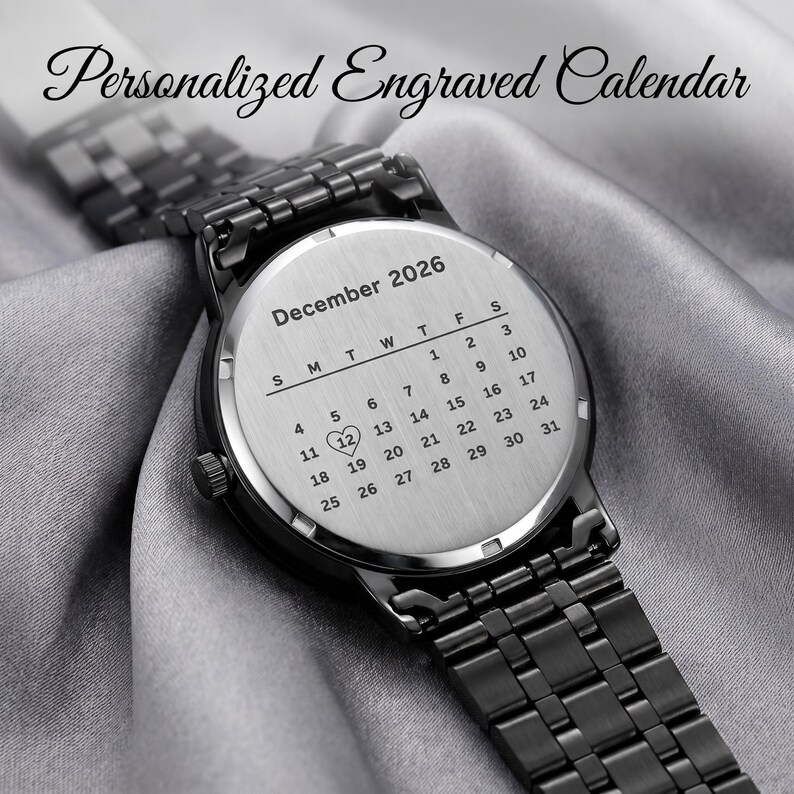 K&ouml;nnte beinhalten: Eine schwarze Armbanduhr mit einem Edelstahl-Kalenderzifferblatt. Das Zifferblatt ist mit dem Monat Dezember 2026 graviert und das Datum des 12. ist mit einem Herzsymbol hervorgehoben. Die Uhr hat ein schwarzes Metallarmband und der Text "Personalized Engraved Calendar" steht oben.