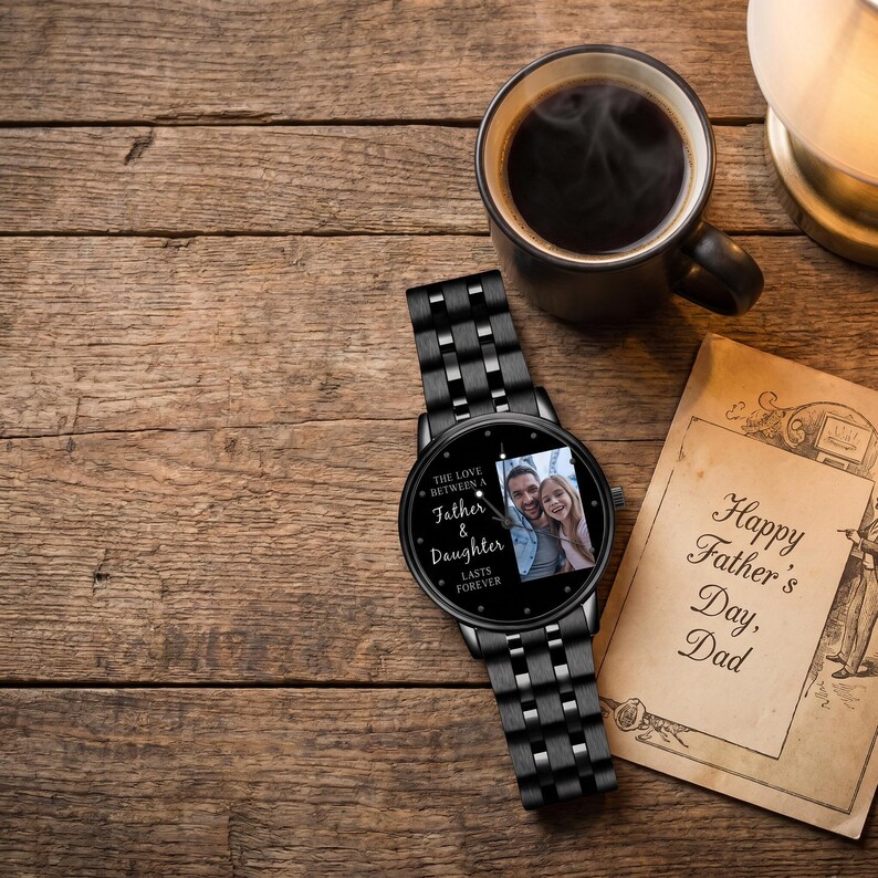 May include: Black wristwatch with a photo of a father and daughter on the watch face. The watch has a black metal band and the words "The Love Between a Father & Daughter Lasts Forever" are printed on the watch face. A Father's Day card and a cup of coffee are also in the image.
