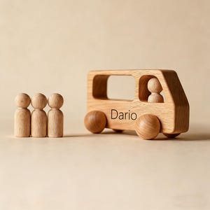Könnte beinhalten: Holzspielzeugbus mit dem Namen "Dario" auf der Seite, mit einer Fahrerfigur und drei Holzpuppen. Der Bus hat vier runde Räder und ein rechteckiges Fenster. Die Spielzeuge sind aus hellem Holz gefertigt.