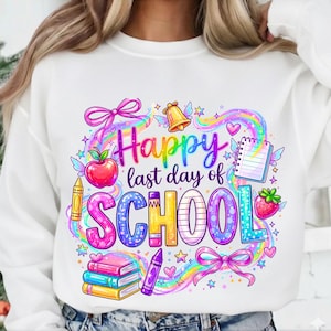 以下が含まれることがあります： 「Happy last day of SCHOOL」と書かれたカラフルなグラフィックが特徴の白いスウェットシャツ。デザインには、虹、リンゴ、ベル、本、クレヨン、イチゴ、リボンが含まれています。グラフィックは明るい色です。