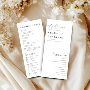 Könnte beinhalten: Zwei weiße Hochzeitskarten mit schwarzem Text. Ein Programm listet die Hochzeitsgesellschaft auf, einschließlich des Geistlichen, der Eltern und der Hochzeitsgesellschaft. Das andere Programm heißt die Gäste zur Hochzeit von Clara und Benjamin willkommen.