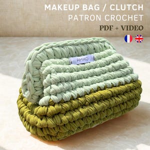 May include: A handmade crochet makeup bag or clutch in shades of green. The bag is made with thick yarn, featuring a textured stitch pattern. The text "MAKEUP BAG / CLUTCH PATRON CROCHET PDF + VIDEO" is displayed at the top.