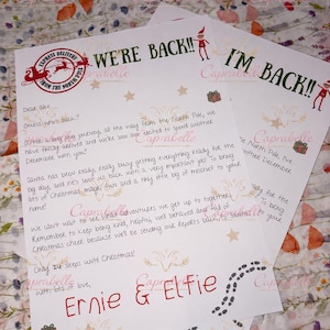 May include: Two white paper letters with green and red text featuring a North Pole express delivery stamp, elf illustrations, and the handwritten names Ernie & Elfie. The letters include printed messages about returning for December and Christmas.