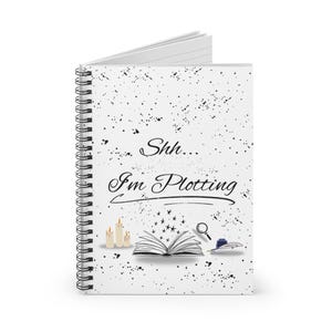 May include: A spiral-bound notebook with a white cover featuring the text "Shh... I'm Plotting." The cover is decorated with black speckles, illustrations of candles, an open book, a magnifying glass, and a quill and inkwell.