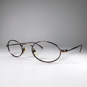 May include: Oval-shaped eyeglasses featuring a thin, dark brown metal frame with a subtle tortoiseshell pattern. The glasses include adjustable nose pads and slender temples, providing a lightweight and functional design for vision correction.