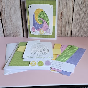 May include: Easter craft kit with a greeting card featuring a colourful egg design, patterned paper, and a diagram. The card has a green border and decorative edges. Includes envelopes and a list of numbers.