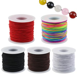 Puede incluir: Cinco carretes de cordón elástico en rojo, multicolor, negro, marrón y blanco. Cada carrete es de plástico blanco y contiene un solo color de cordón. Se muestra una cuerda con cinco cuentas lisas y redondas en amarillo, negro, blanco, rosa y rojo.