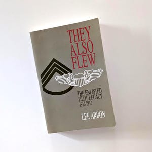 May include: A book titled "They Also Flew" with red text on a gray cover. The cover features a black and white military insignia and the text "The Enlisted Pilot Legacy 1912-1942" and the author's name, Lee Arbon.