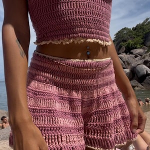 Puede incluir: Conjunto de dos piezas de ganchillo en tonos rosas. El top es de estilo halter y los shorts son de cintura alta. Ambas piezas tienen un ribete festoneado en un color m&aacute;s claro. Ideal para ropa de playa o verano.