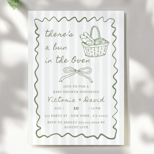 Può includere: Un invito per un baby shower con uno sfondo a righe verdi e bianche. L'invito presenta il testo "there's a bun in the oven" e i dettagli del baby shower di Victoria e David. L'invito è modificabile in Canva.