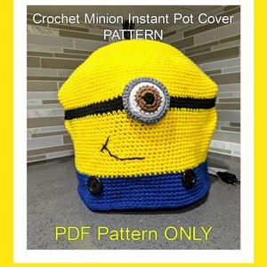 May include: Crochet Minion Instant Pot Cover PATTERN. A yellow crochet cover for an Instant Pot, shaped like a Minion from the Despicable Me movies. The cover has a black strap, a large gray eye with a brown pupil, a black stitched smile, and two black buttons.