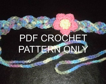 May include: A crochet headband with a pink flower in the center. The headband is made with a multi-colored yarn in shades of blue, green, and purple. The text "PDF CROCHET PATTERN ONLY" is written in white on a black background.