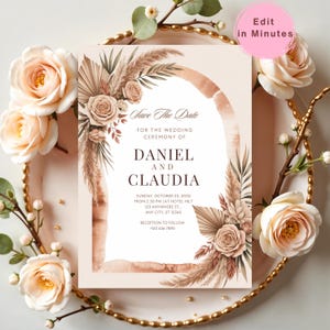 May include: A wedding invitation card with the text "Save The Date" and details for Daniel and Claudia's wedding. The design features a watercolour arch, floral and pampas grass accents in neutral tones, and the words "Edit in Minutes".