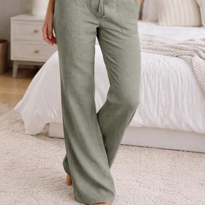 Puede incluir: Pantalones de lino verde salvia con cintura con cordón y bolsillos. El diseño de pernera ancha crea un ajuste relajado y cómodo. Los pantalones forman parte de una colección de ropa informal.