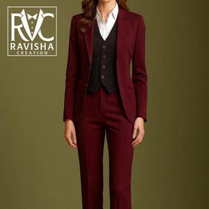 Op de afbeelding: Een bordeauxrood businesspak met een blazer, vest en broek. Het pak wordt gecombineerd met een wit overhemd met kraag. De afbeelding bevat het logo "RAVISHAA CREATION". Het pak is effen van kleur.