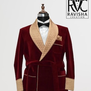 May include: A burgundy velvet smoking jacket with a quilted gold satin shawl collar, cuffs, and pocket trim. The jacket has a matching belt with tassels and a black bow tie. The logo "RAVISHA CREATION" is in the upper right corner.