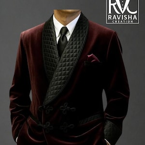 May include: A burgundy velvet blazer with a black quilted shawl collar, cuffs, and pocket square. The blazer features black decorative buttons and a white dress shirt and black tie. The logo "RAVISHA CREATION" is in the upper right corner.