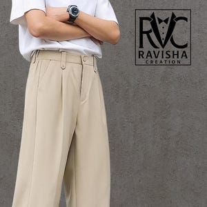 May include: Beige wide-leg pants with a pleated front. The pants have a high waist and a straight leg design. The pants are paired with white sneakers. The image also includes the text "RAVISHA CREATION".