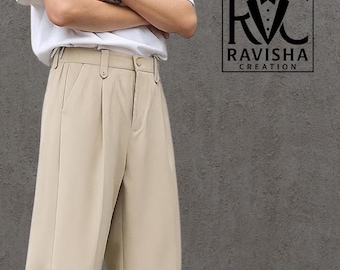May include: Beige wide-leg pants with a pleated front. The pants have a high waist and a straight leg design. The pants are paired with white sneakers. The image also includes the text "RAVISHA CREATION".